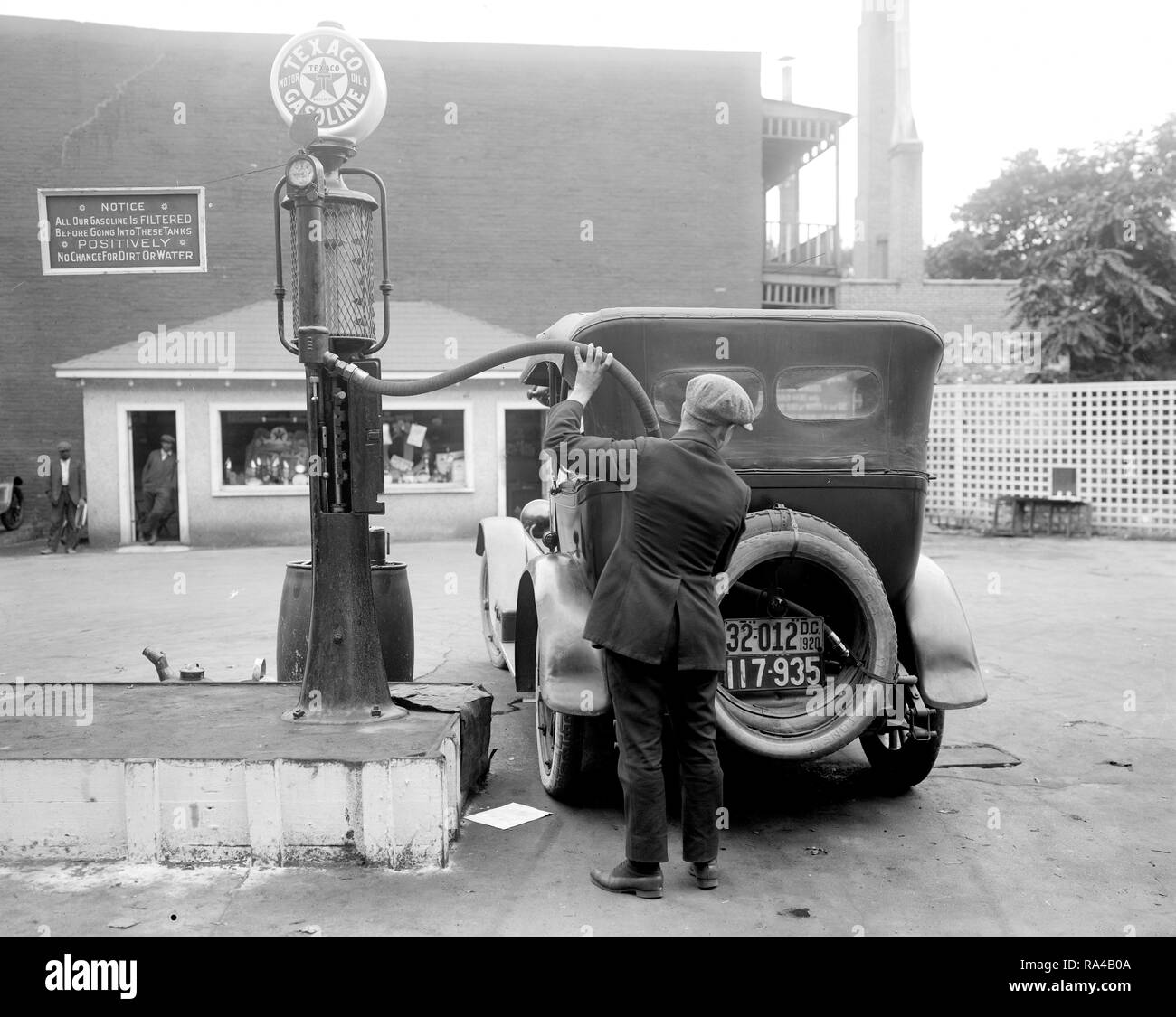 Man pumping gas into his automobile in early 1900s at Texaco Gas Station  with Texaco Gasoline (1910s possibly Stock Photo