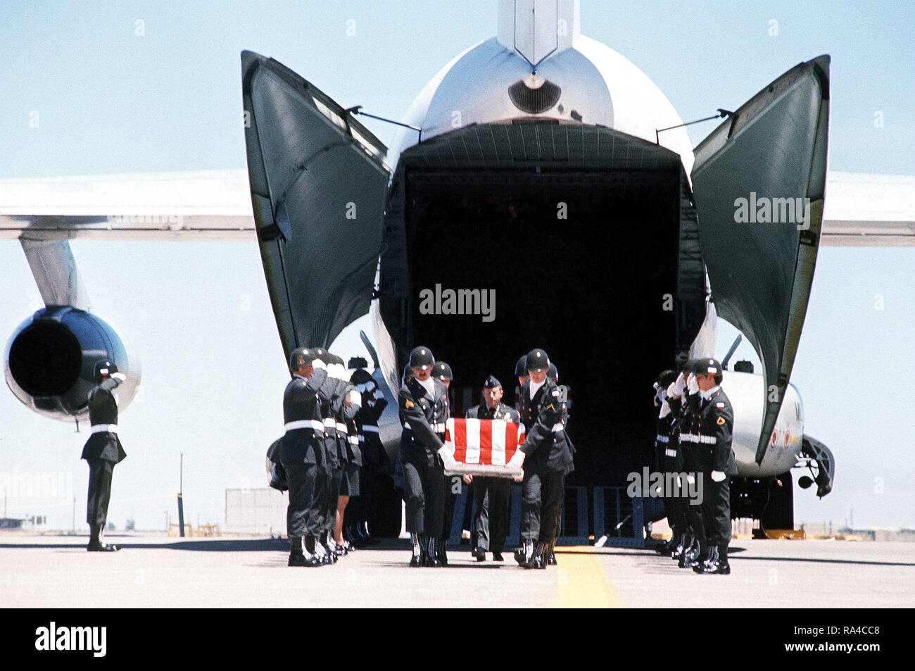 1977 - An Army color guard stands at attention as pallbearers remove the caskets of three U.S. Army soldiers who were killed in a helicopter crash in Korea. Stock Photo