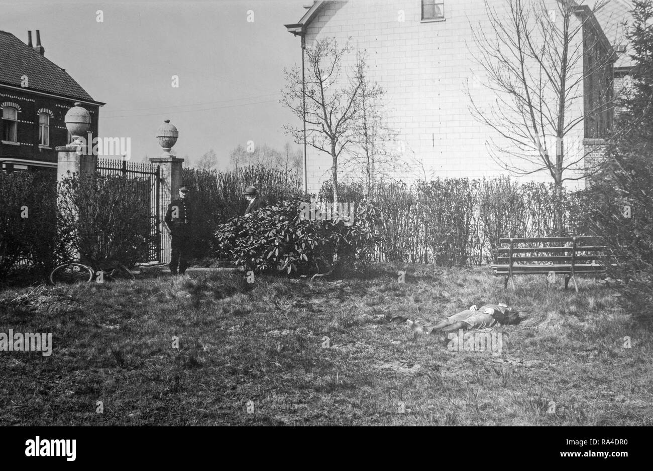 Mid twentieth century black and white photo showing police officer / gendarme, inspector and murdered woman at crime scene in garden Stock Photo