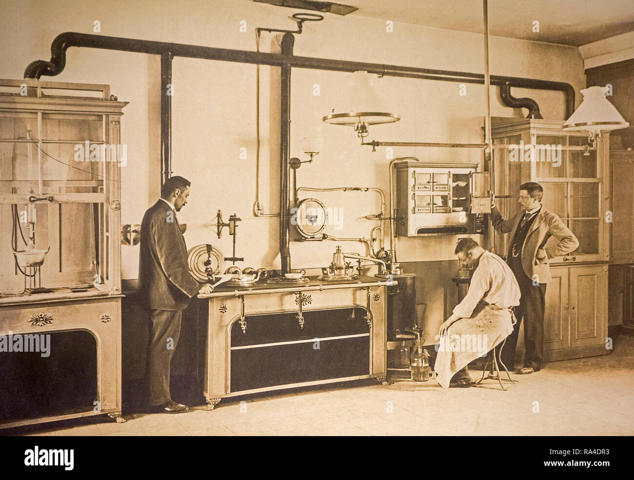 Early twentieth century archival photograph of scientist and police inspectors working in forensic laboratory looking for crime evidence Stock Photo