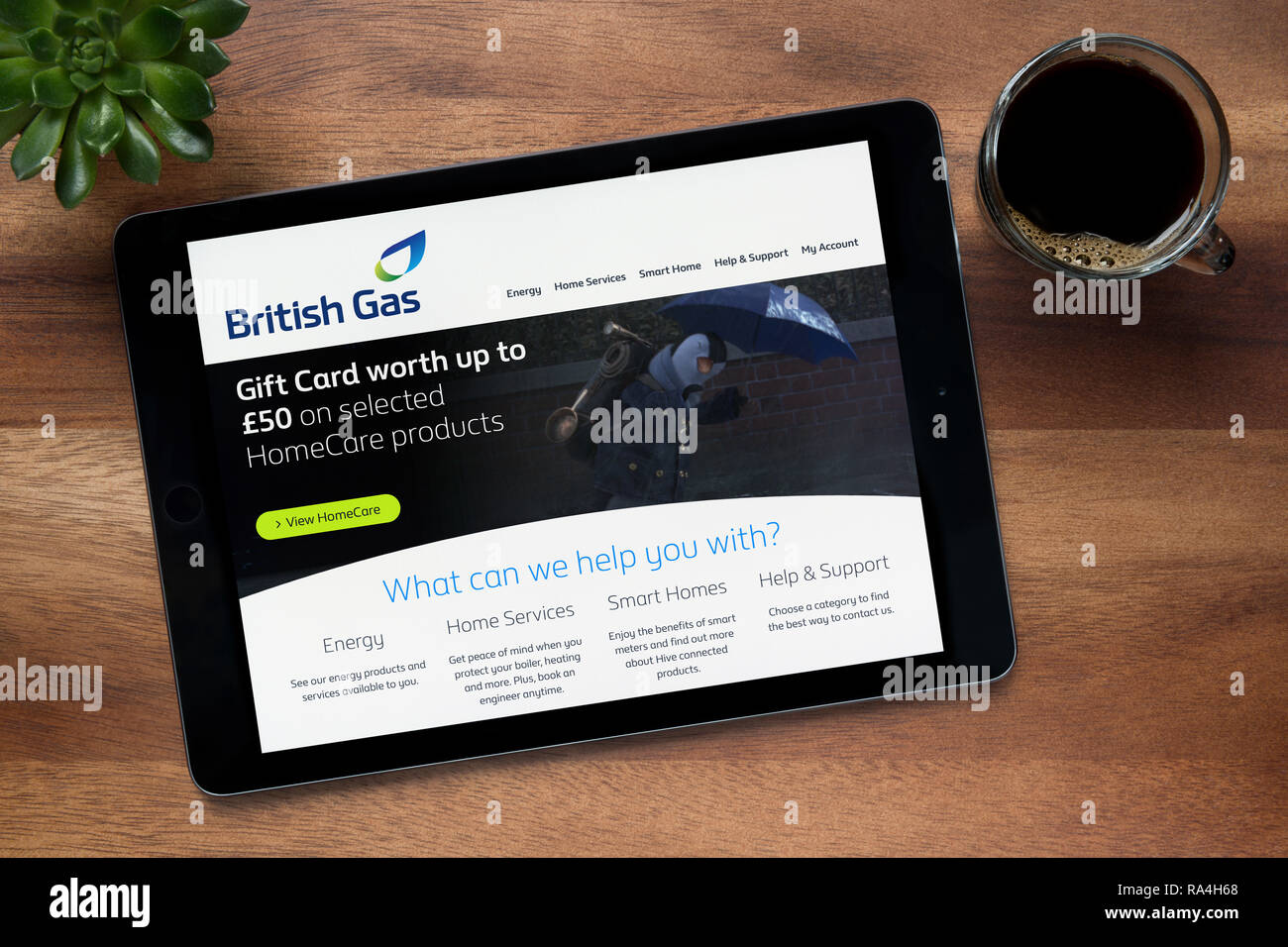 The website of British Gas is seen on an iPad tablet, on a wooden table along with an espresso coffee and a house plant (Editorial use only). Stock Photo