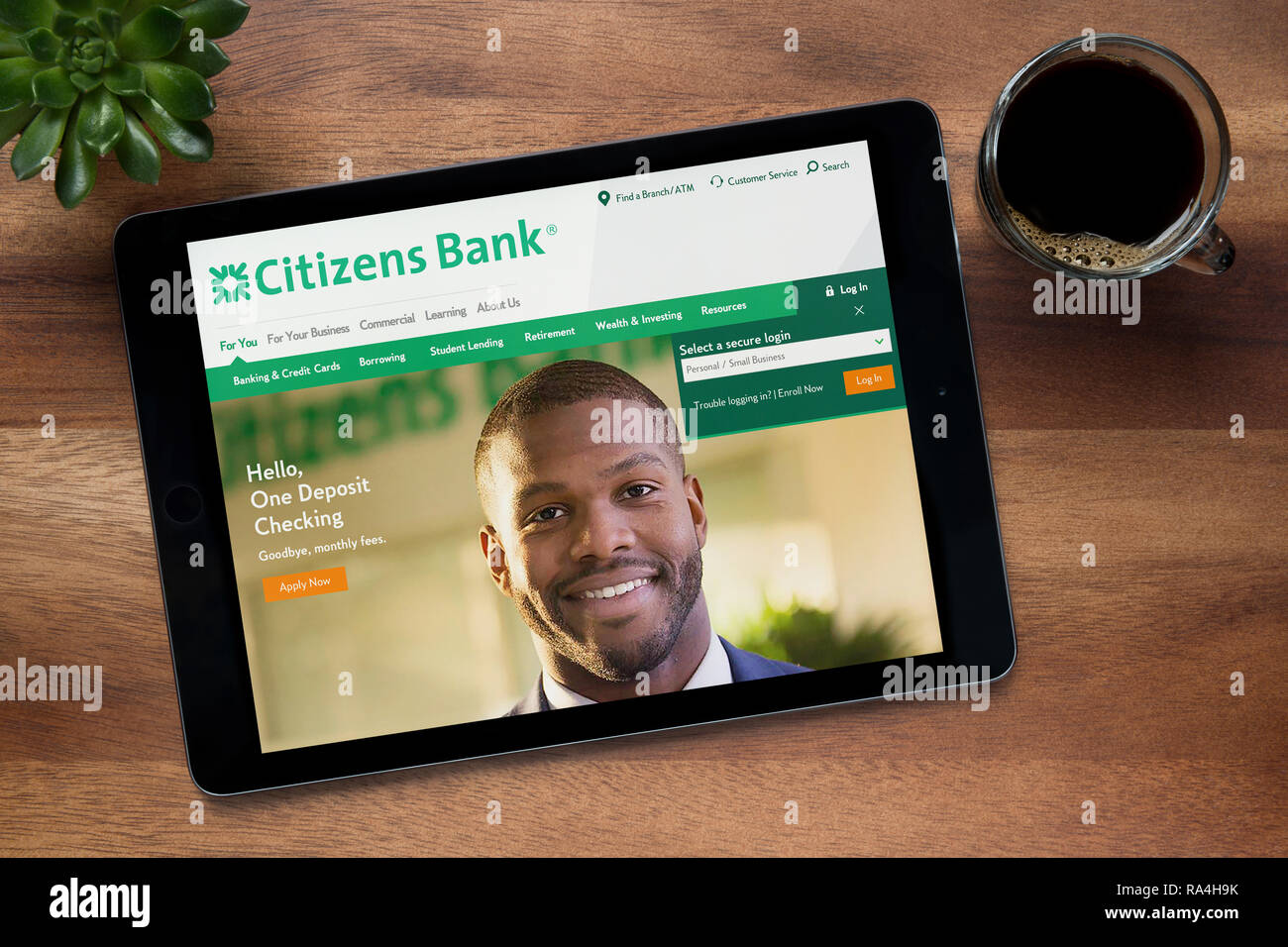 The website of the Citizens Bank is seen on an iPad tablet, on a wooden table along with an espresso coffee and a house plant (Editorial use only). Stock Photo