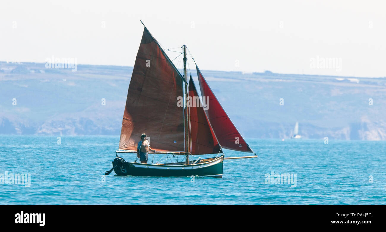 Old fishing boat at sea with red sails, Cornwall, UK. Stock Photo