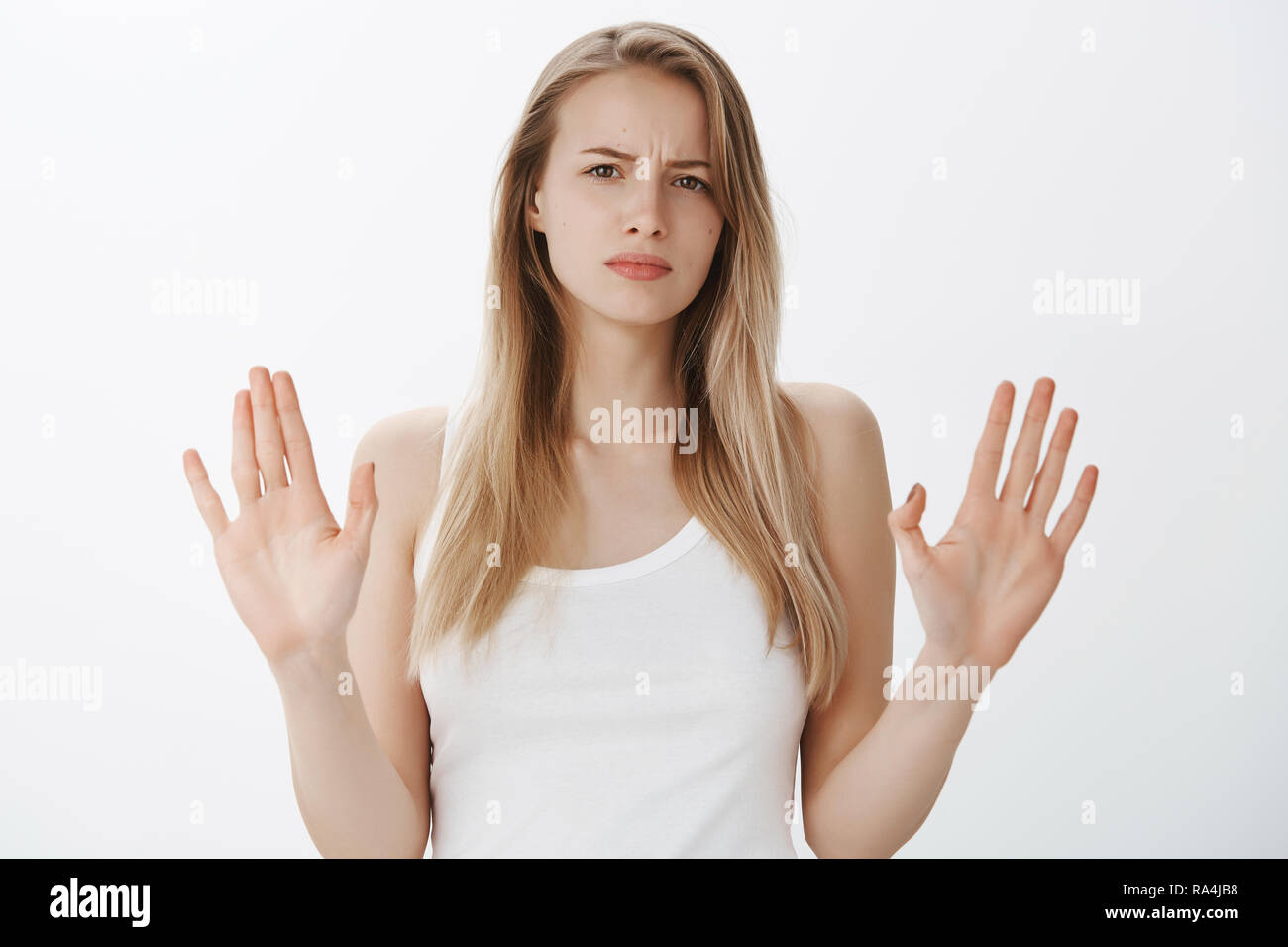 Stop, enough of lies. Portrait of displeased and sad cute bothered woman with fair hair frowning from dislike sweeping hands in enough and not gesture, giving refusal and firm no. Stock Photo