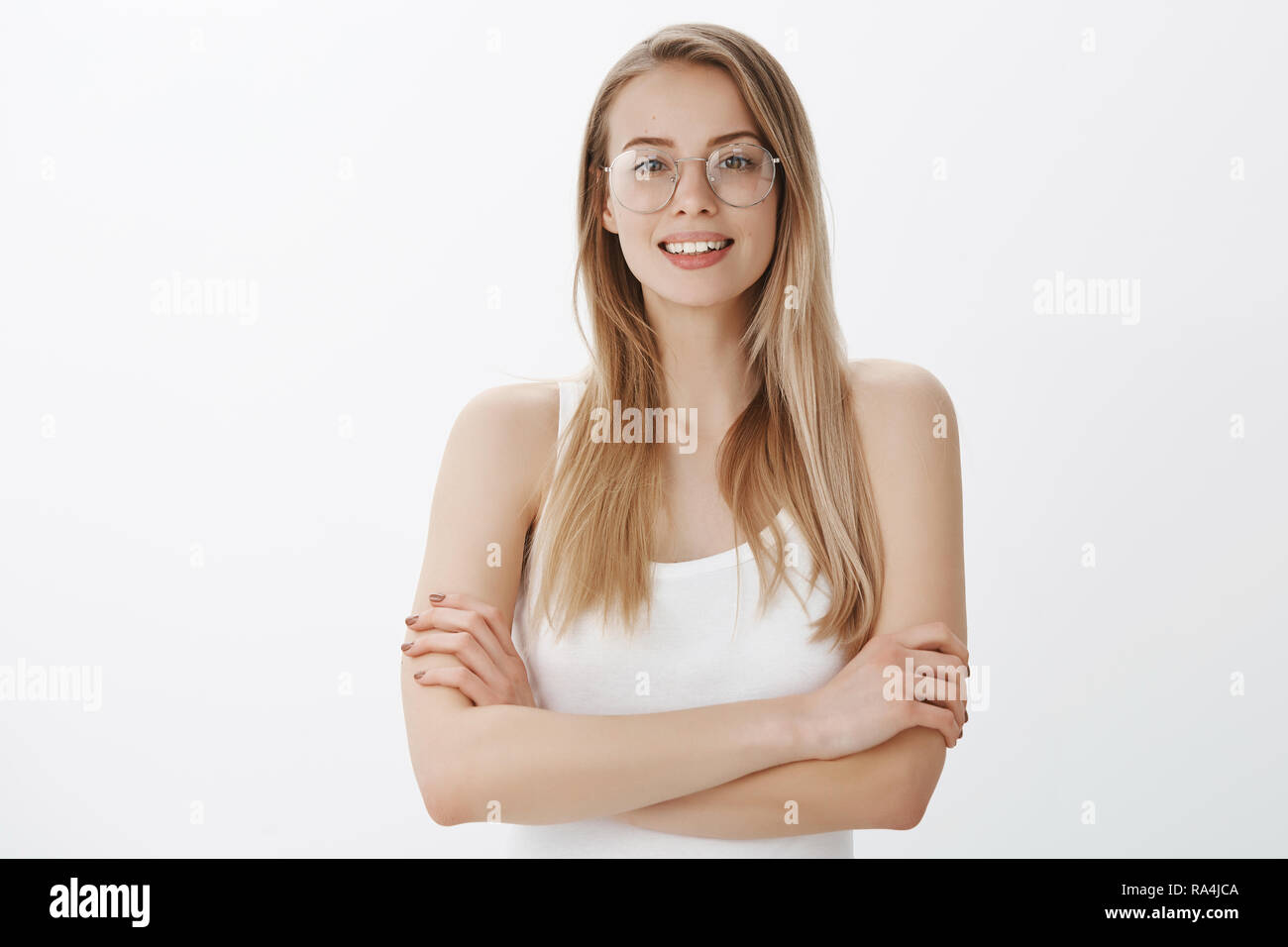 Confident and ambitious woman dreaming become director of company ready to work hard and determined holding hands crossed on chest in self-assured pose, smiling assertive over gray wall Stock Photo