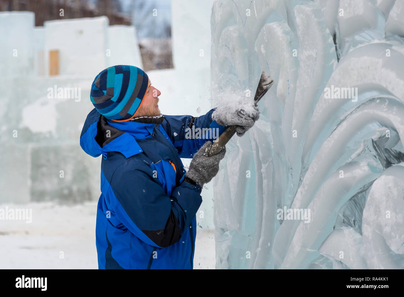The sculptor cuts an ice figure for Christmas from a block of ice with ...