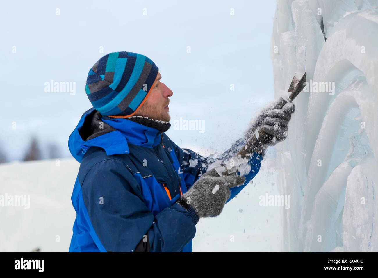 The sculptor cuts an ice figure for Christmas from a block of ice with ...