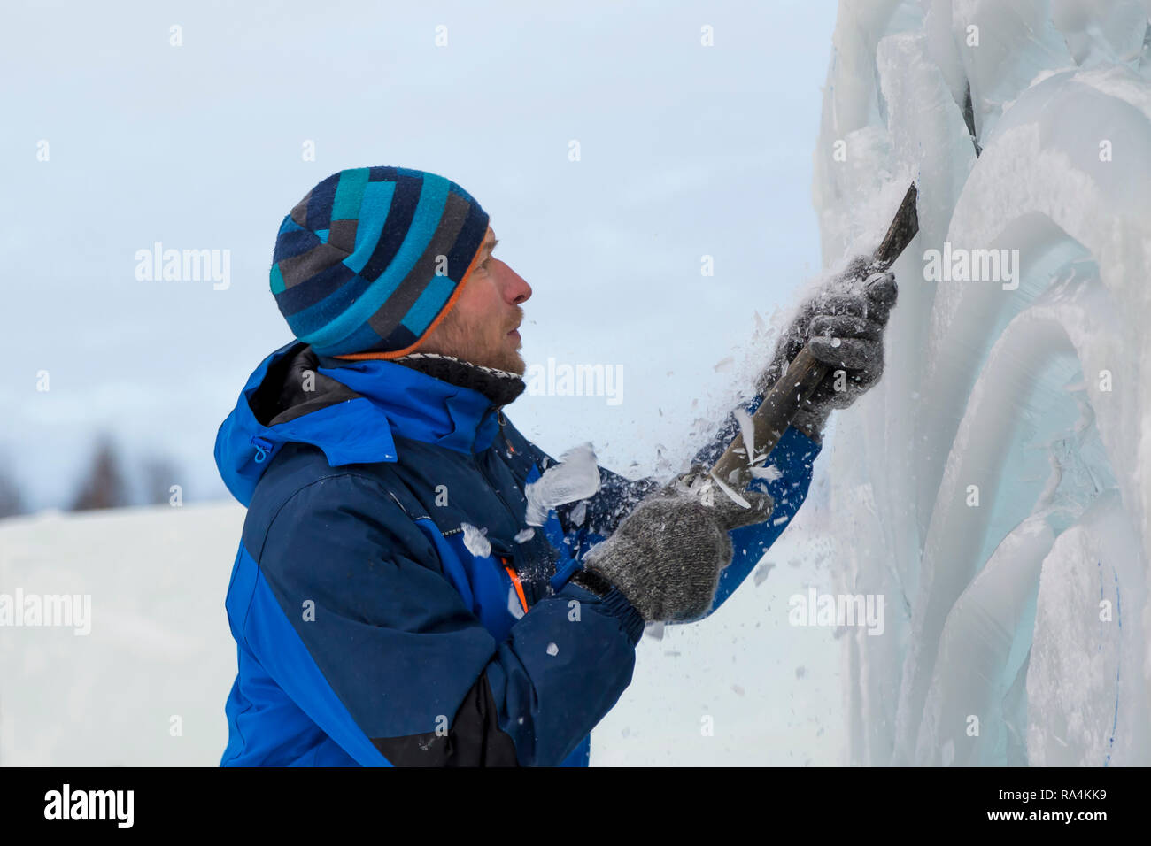 The sculptor cuts an ice figure for Christmas from a block of ice with ...