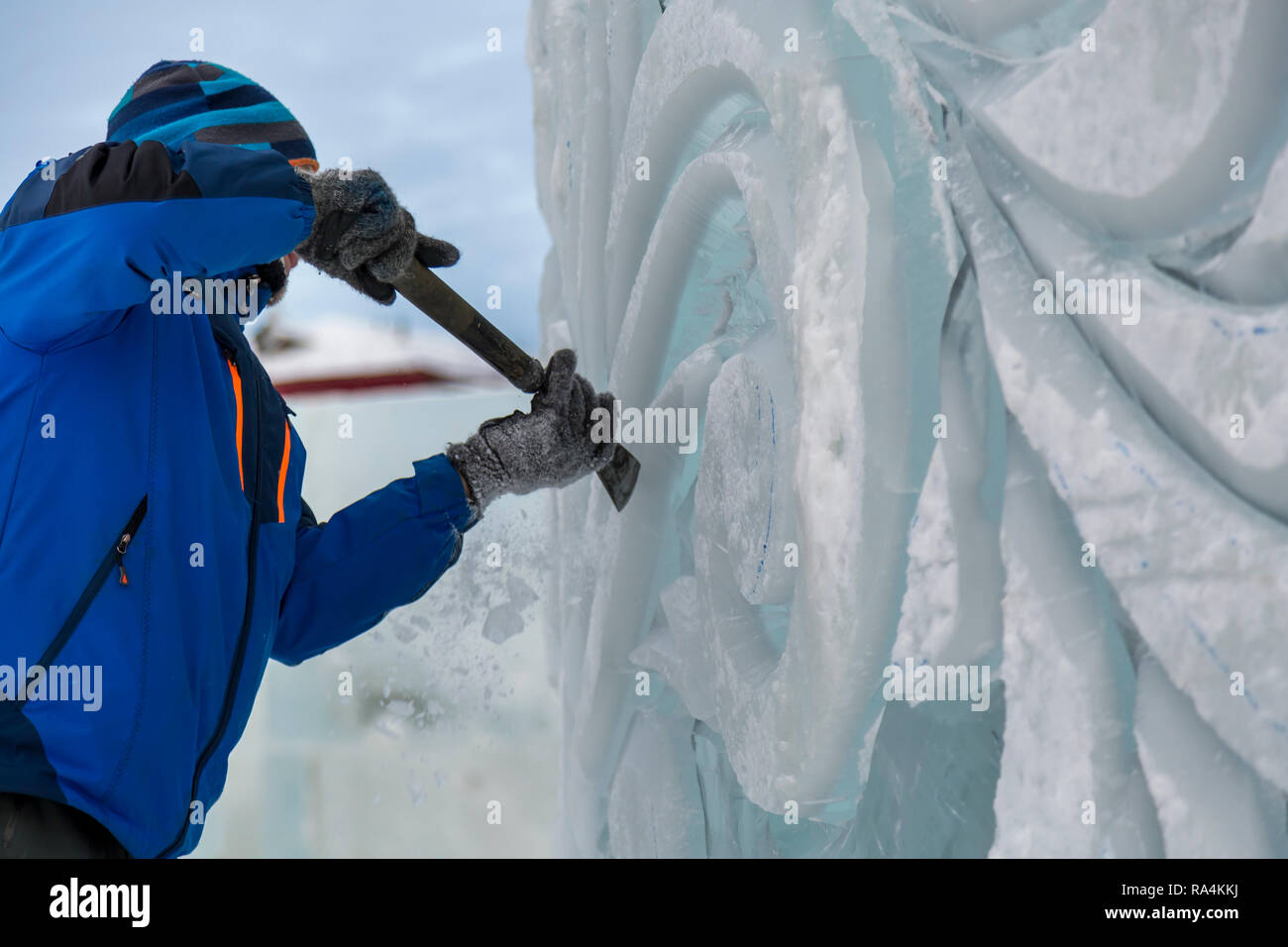 The sculptor cuts an ice figure for Christmas from a block of ice with ...