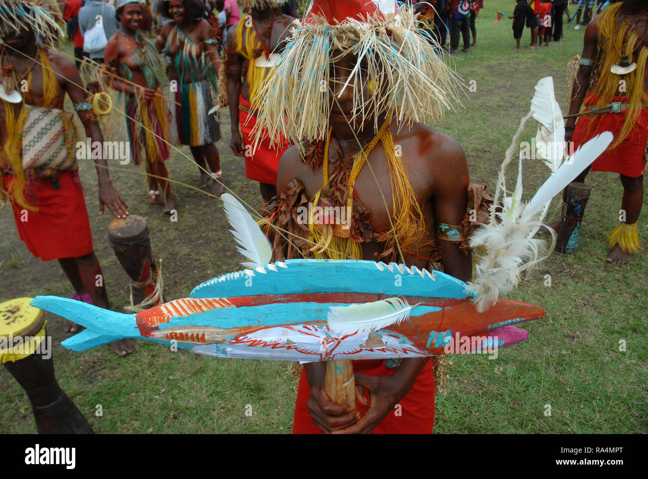 Colourfully dressed and face painted man holding a model of a fish as part of a Sing Sing in Madang, Papua New Guinea. Stock Photo
