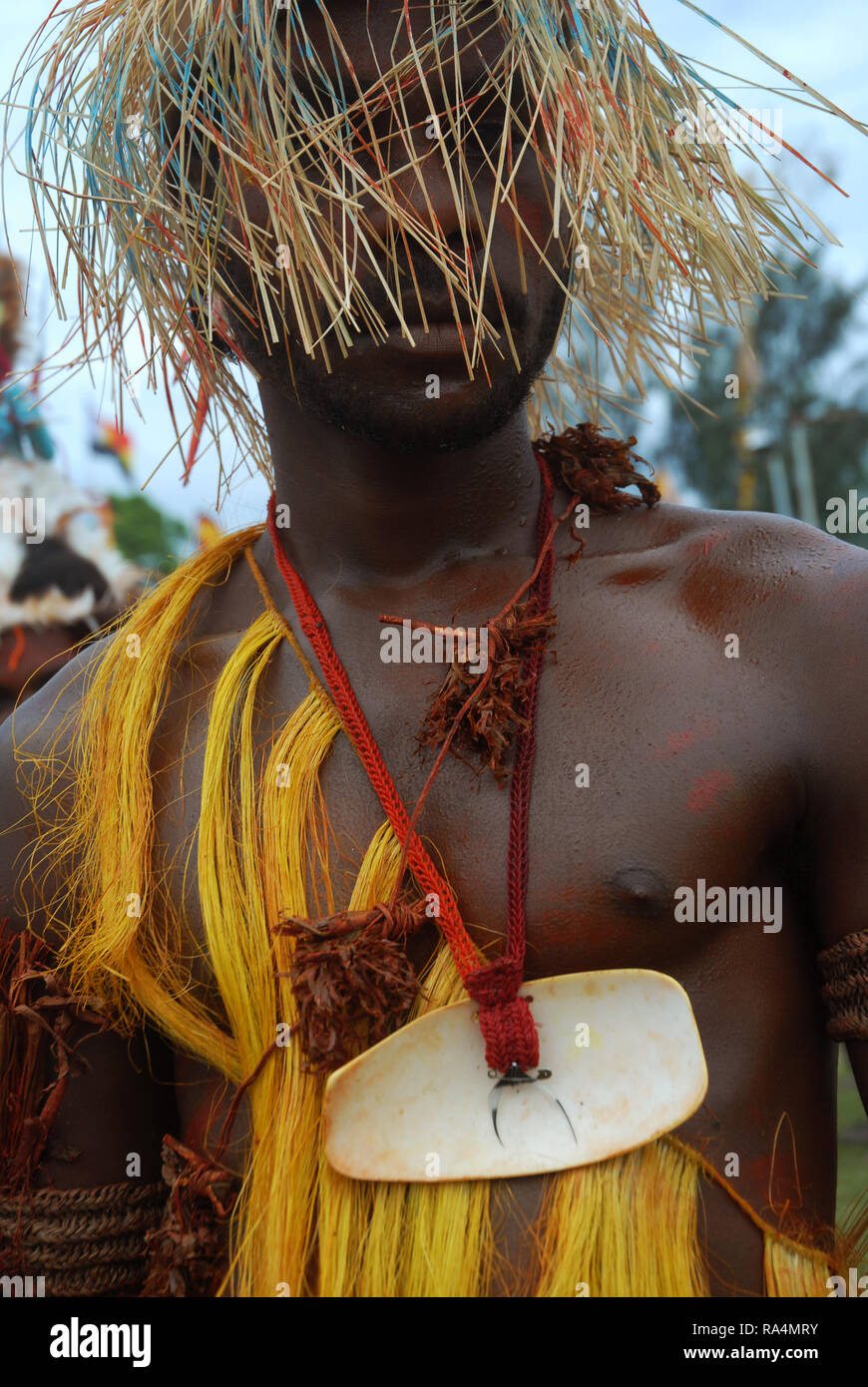 Colourfully dressed and face painted man wearing a straw hat as part of a Sing Sing in Madang, Papua New Guinea. Stock Photo