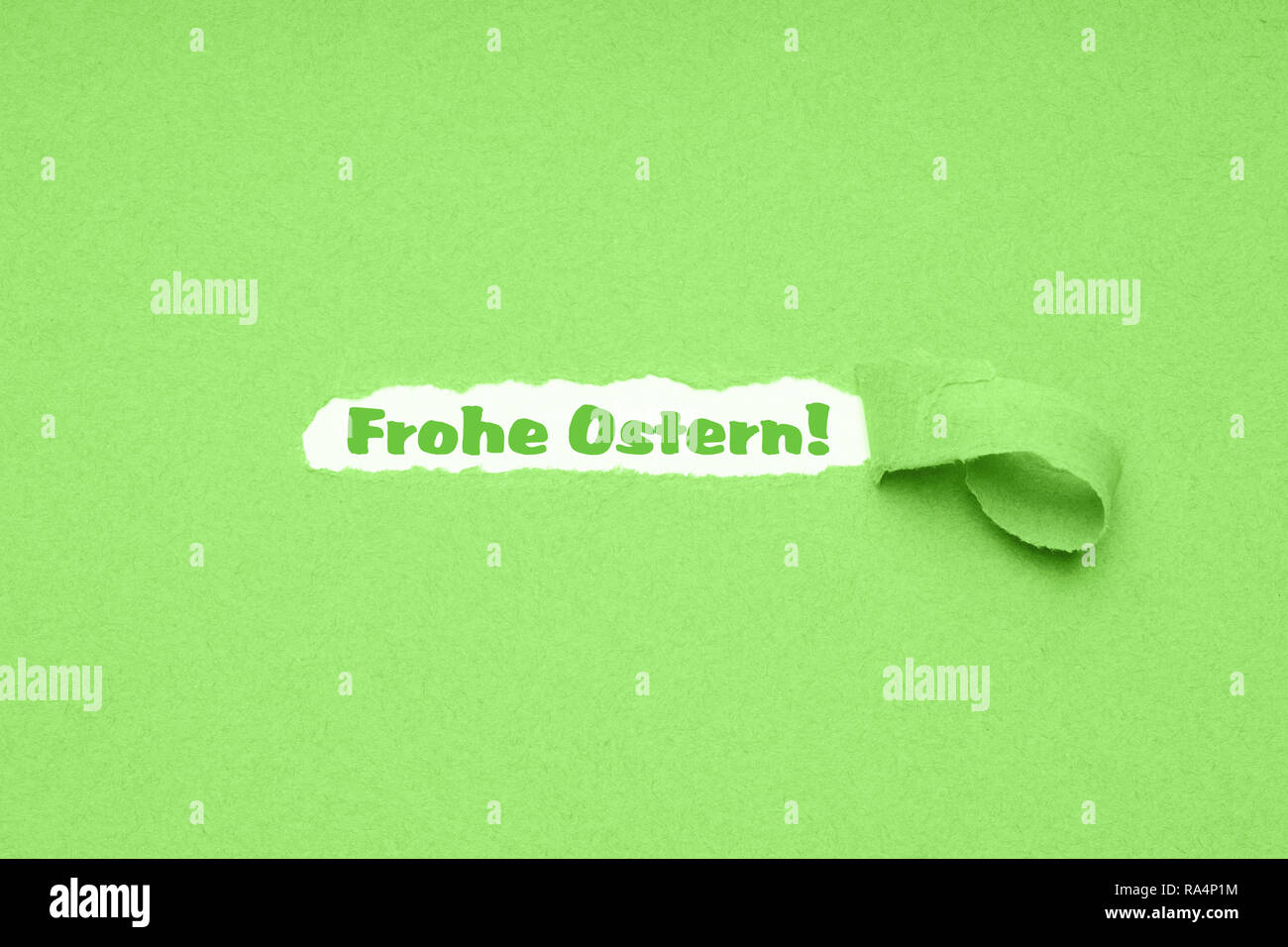 Frohe Ostern is German for Happy Easter - hole torn in green paper background to reveal easter greeting Stock Photo