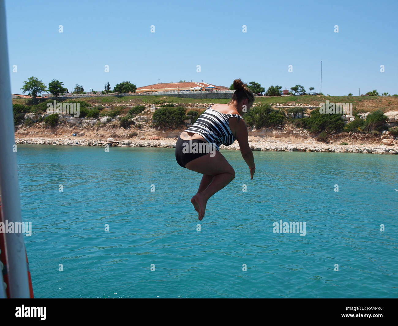 Young Woman having fun on holiday, Diving off the side of a boat Stock