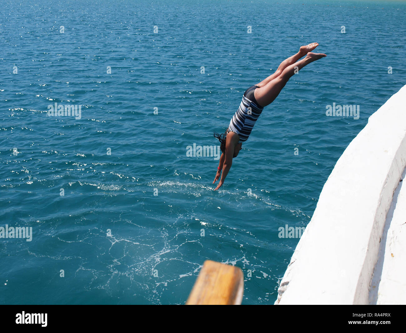 Young Woman having fun on holiday, Diving off the side of a boat Stock