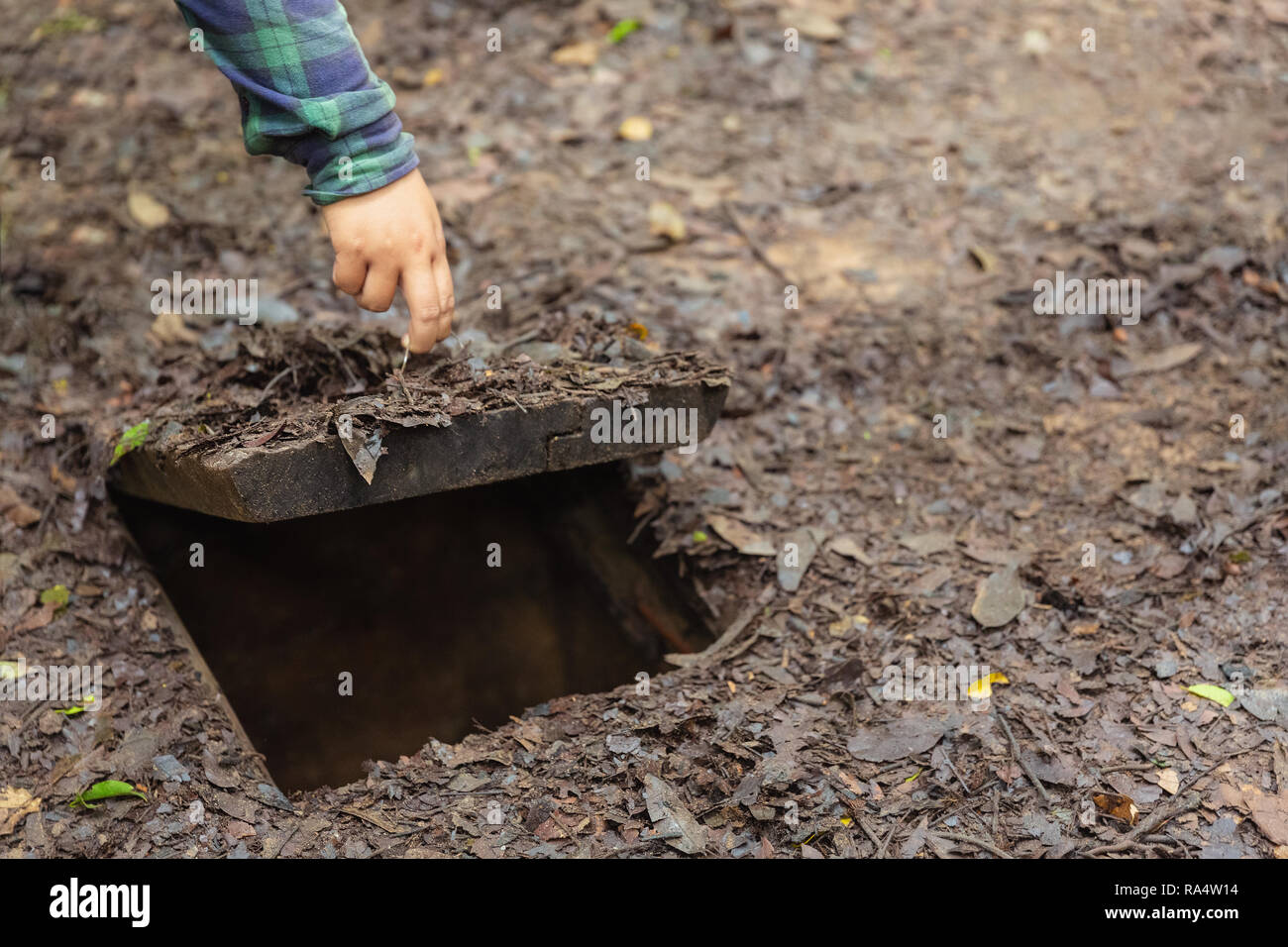 Handing holding open door into a tunnel at the Cu Chi Tunnels War Memorial in Ho Chi Minh City