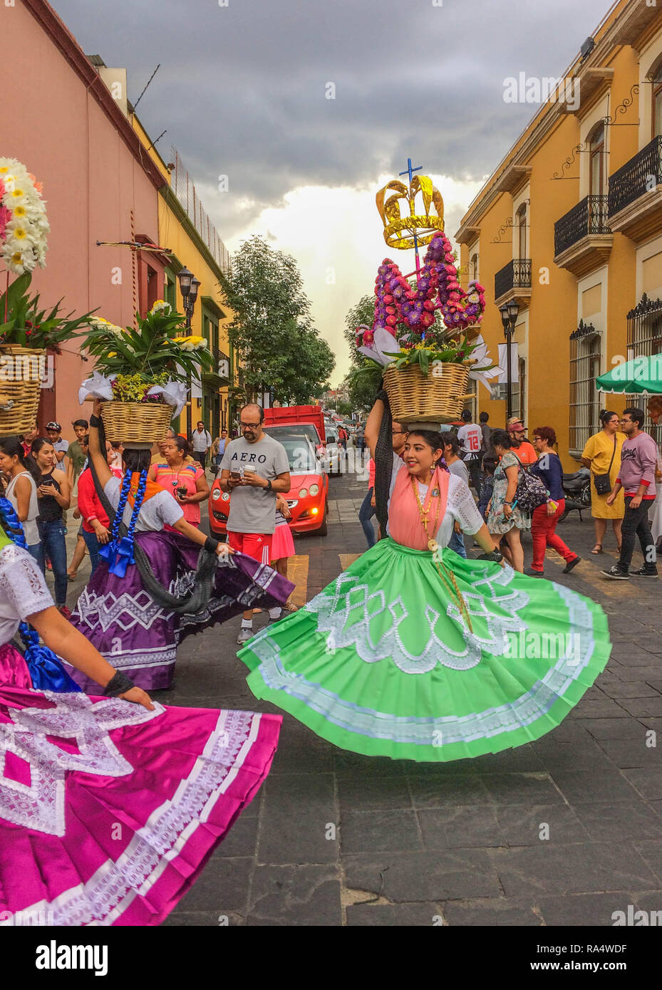 Beautiful dancers in colorful traditional dresses and head baskets, dancing  on the street during a Guelaguetza parade, in Oaxaca, Mexico Stock Photo -  Alamy