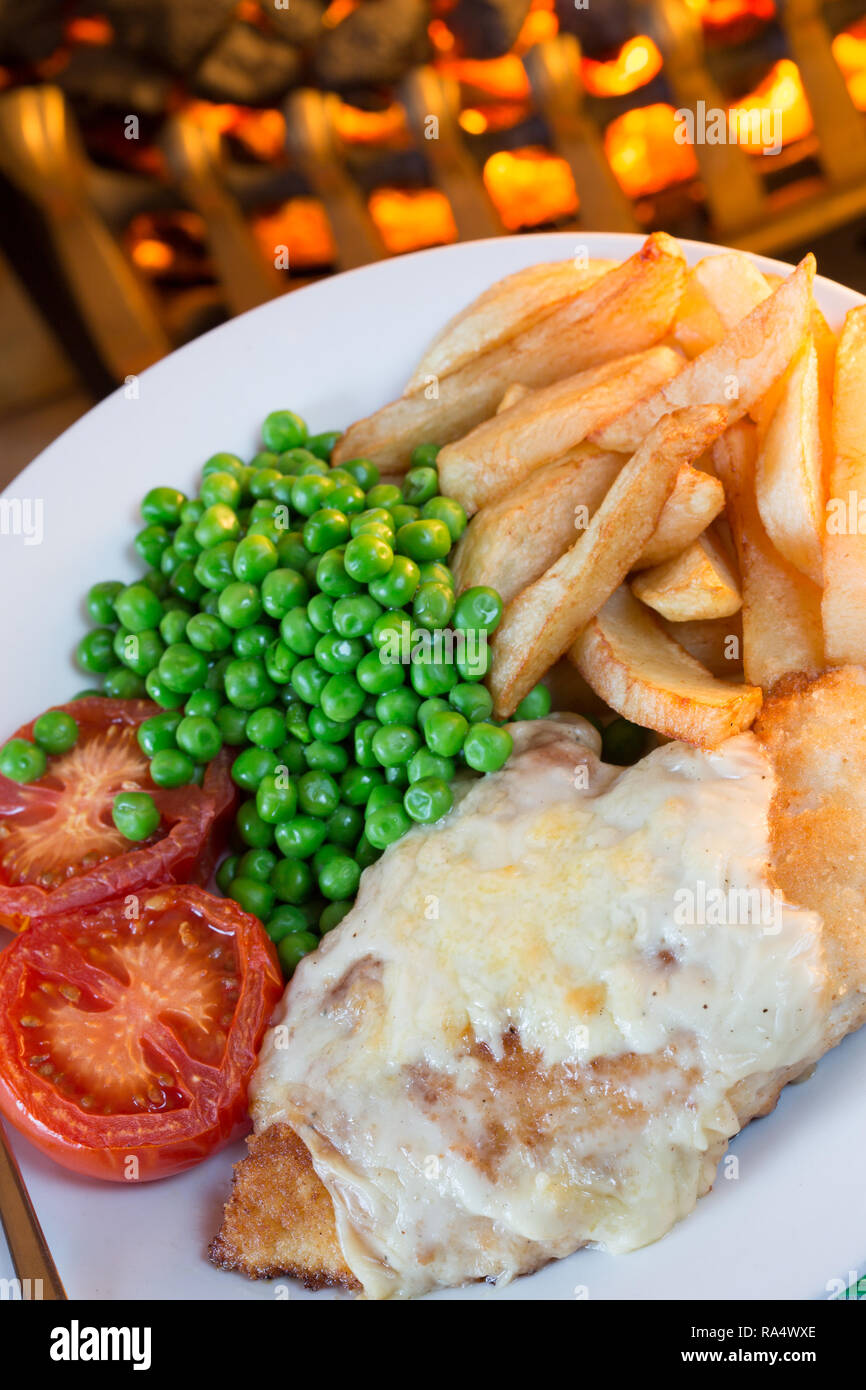 A popular Teeside delicacy of Chicken parmo with Chips/fries, garden peas and grilled tomato. Stock Photo
