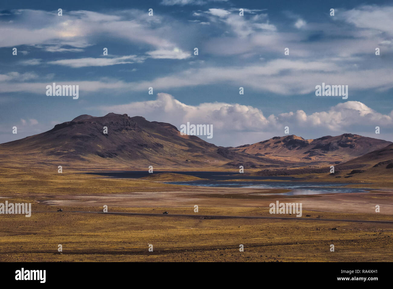 Valley with lakes in Peruvian highland landscape, gentle mountains in distance and clouds in blue sky Stock Photo