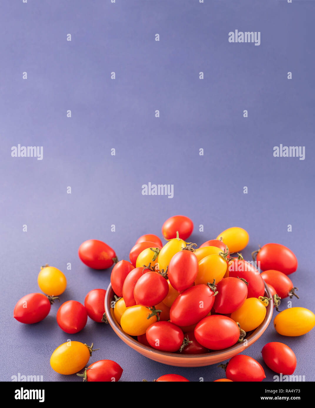Fresh cherry tomatoes in a wooden bowl isolated on a blue background ...