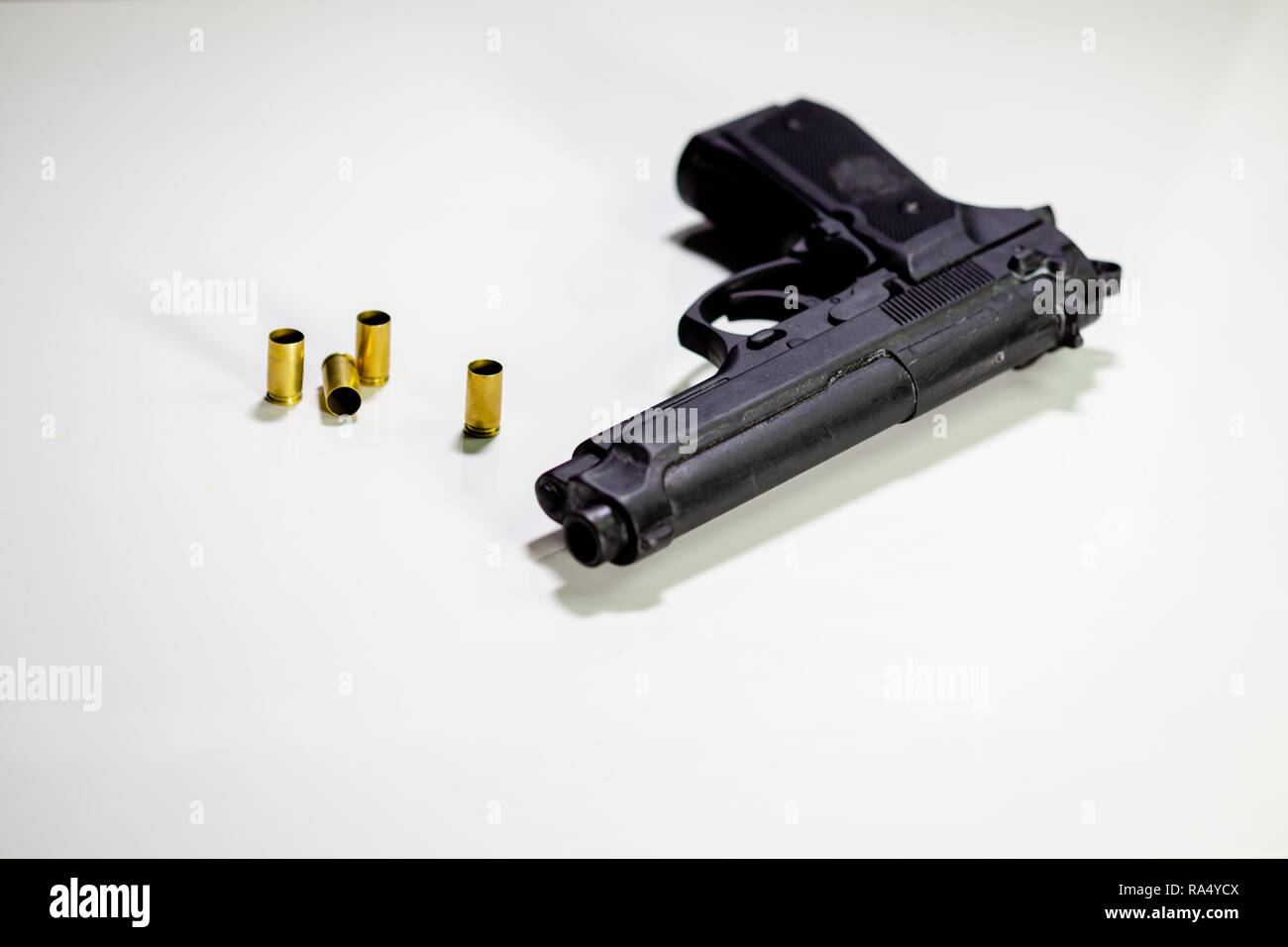 Pistol with 9mm shell casings on white table Stock Photo - Alamy