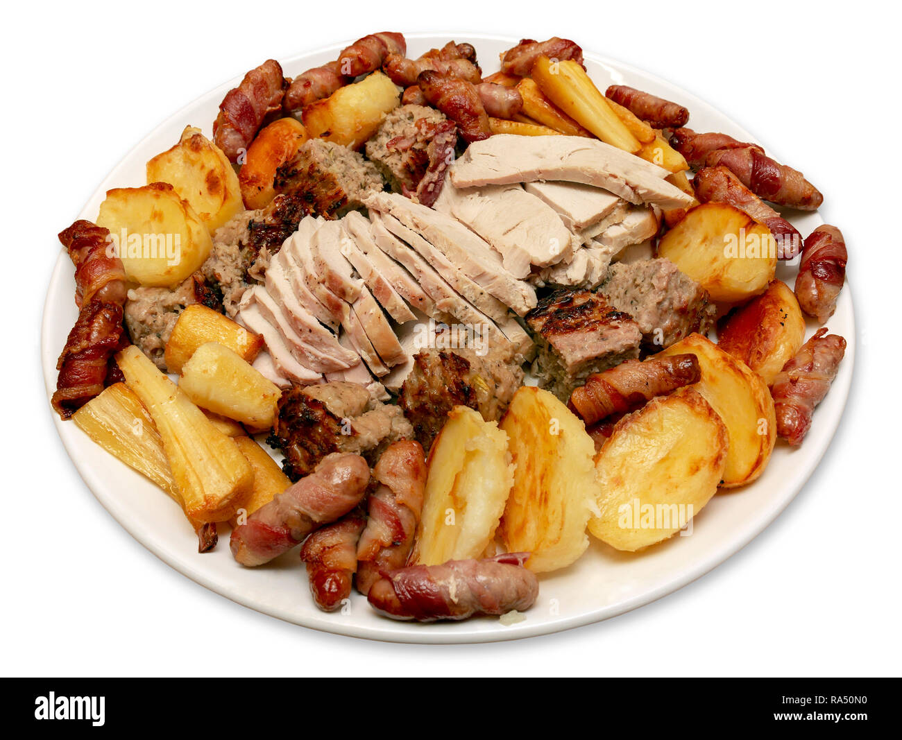Roast turkey dinner serving platter with potatoes, parsnips, pigs in blankets and stuffing on an isolated white background Stock Photo