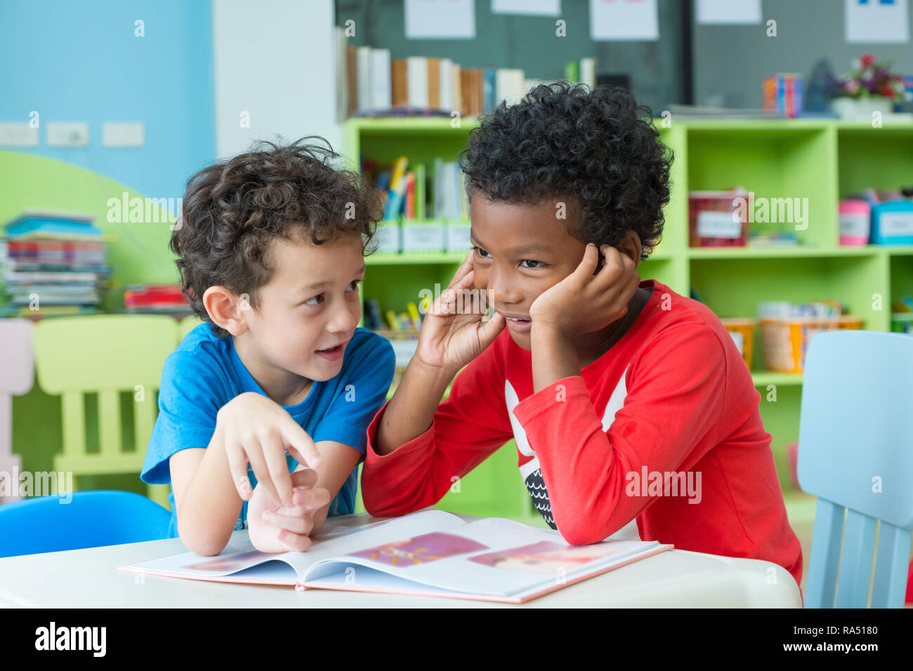 Two boy kid sit on table and reading tale book in preschool library,Kindergarten school