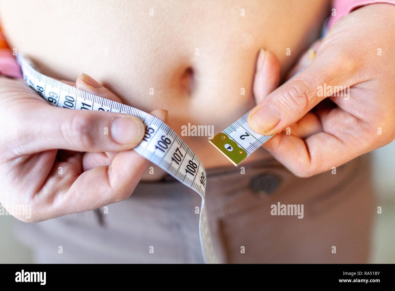 woman measures her abdomen with a measuring tape Stock Photo