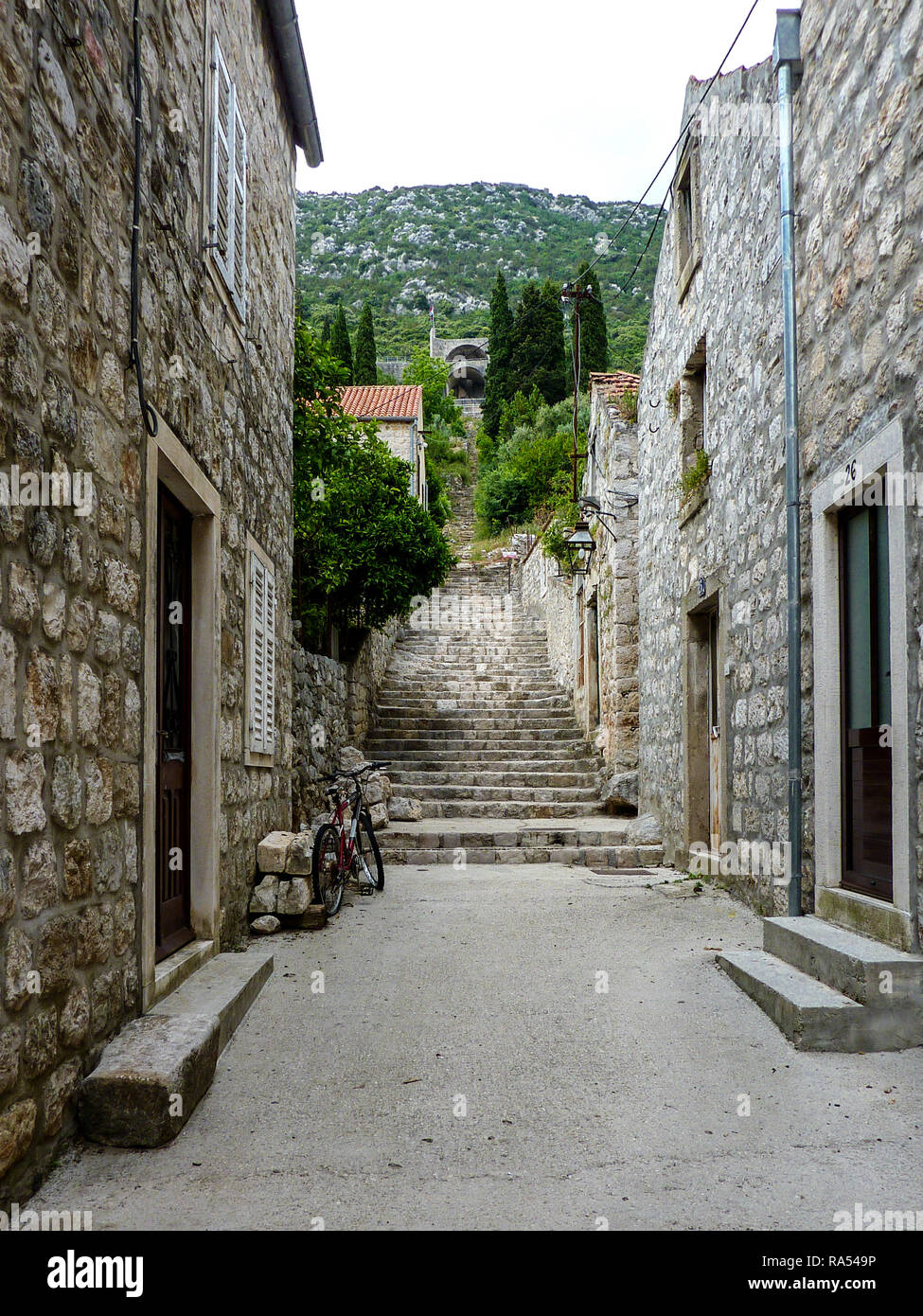 Steps rising through the village of Ston in Croatia with a view of the walls at the top Stock Photo