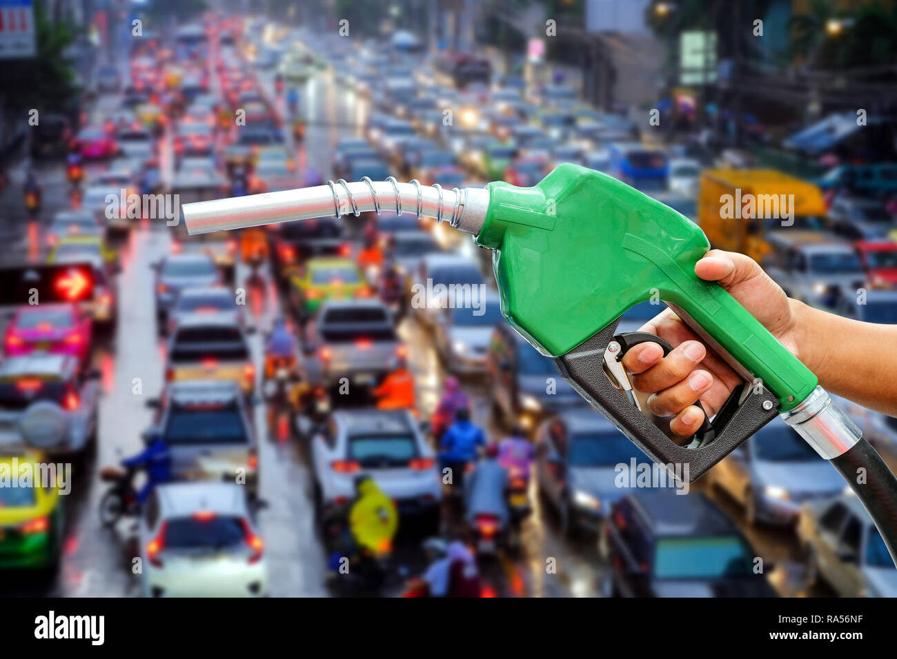 Right hands of men who were holding an automatic nozzle to make refill oil on traffic jam blurred background with concept idea. Stock Photo