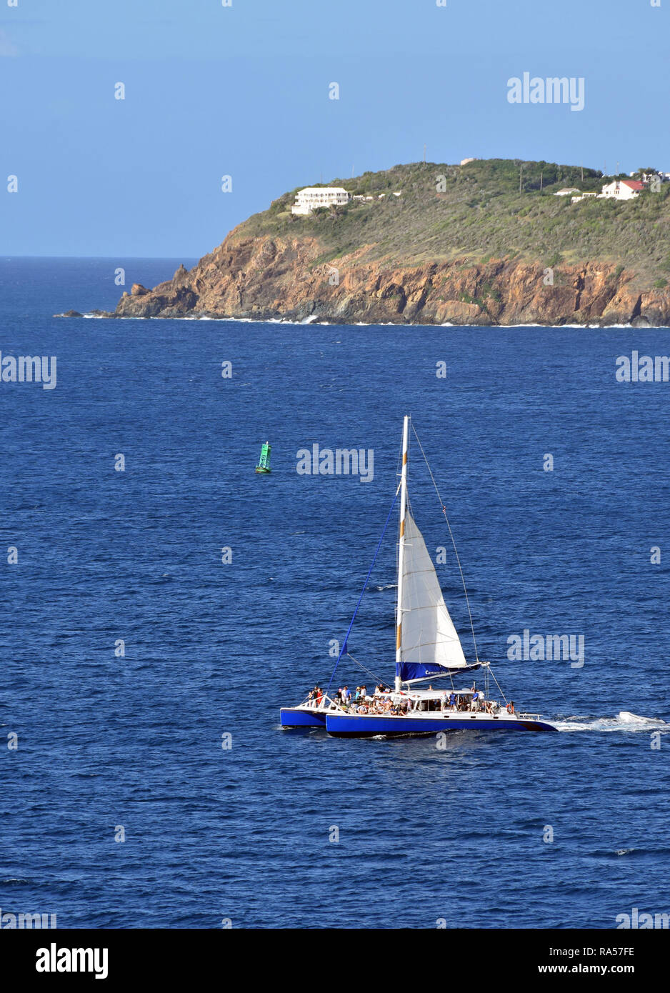 catamaran with passengers near Caribbean island surrounded by blue water Stock Photo