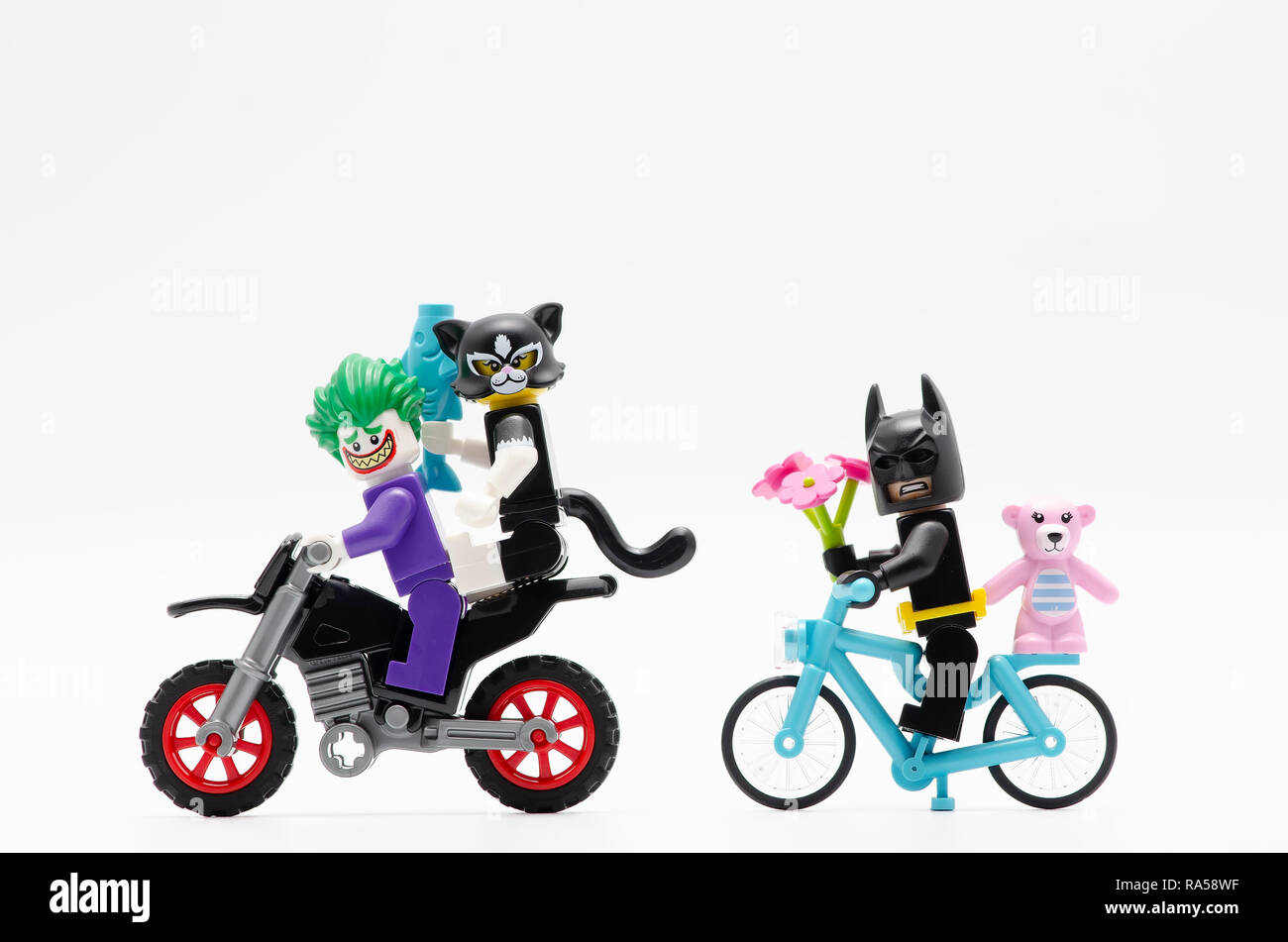 joker riding motorcycle with cat women and batman riding bicycle. Lego minifigures are manufactured by The Lego Group. Stock Photo