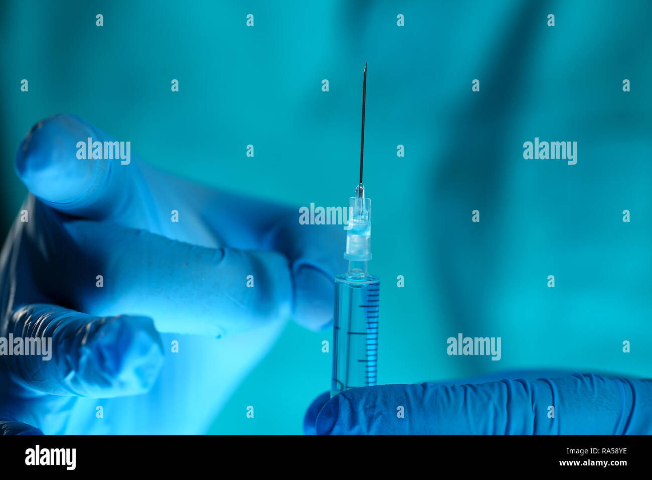 Physician injector arms in sterile uniform holding syringe Stock Photo