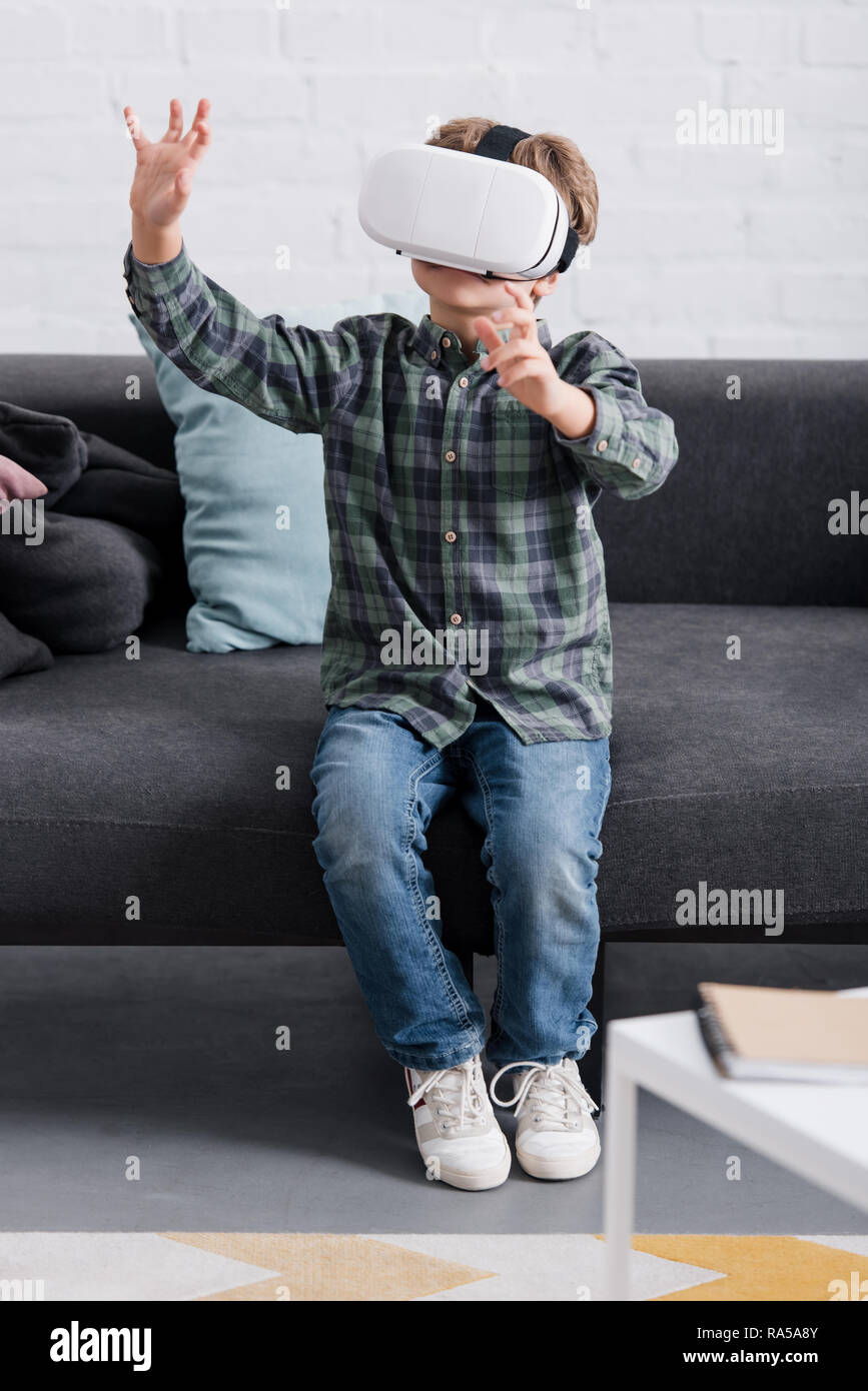 child sitting on couch and using virtual reality headset at home Stock Photo