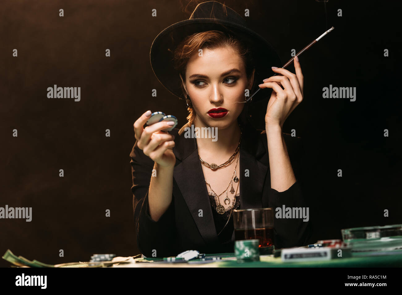 attractive girl in jacket and hat smoking cigarette at poker table in