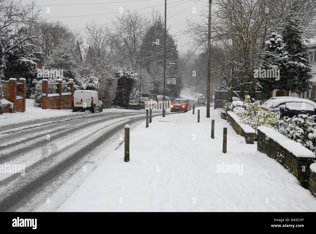 Car negotiating a slight incline during falling snow, England Stock Photo