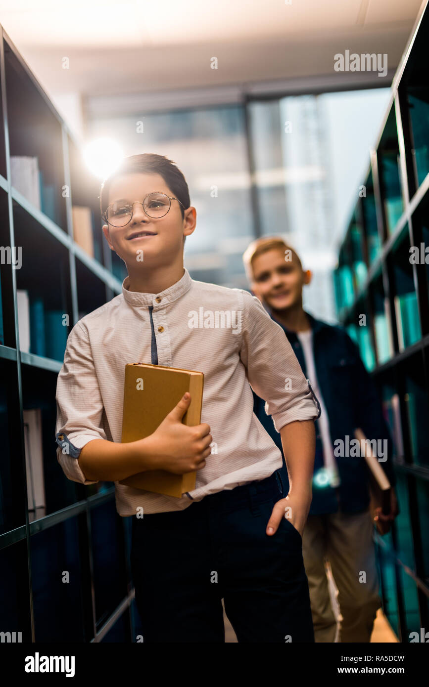 cute smiling schoolboys holding books in library Stock Photo - Alamy