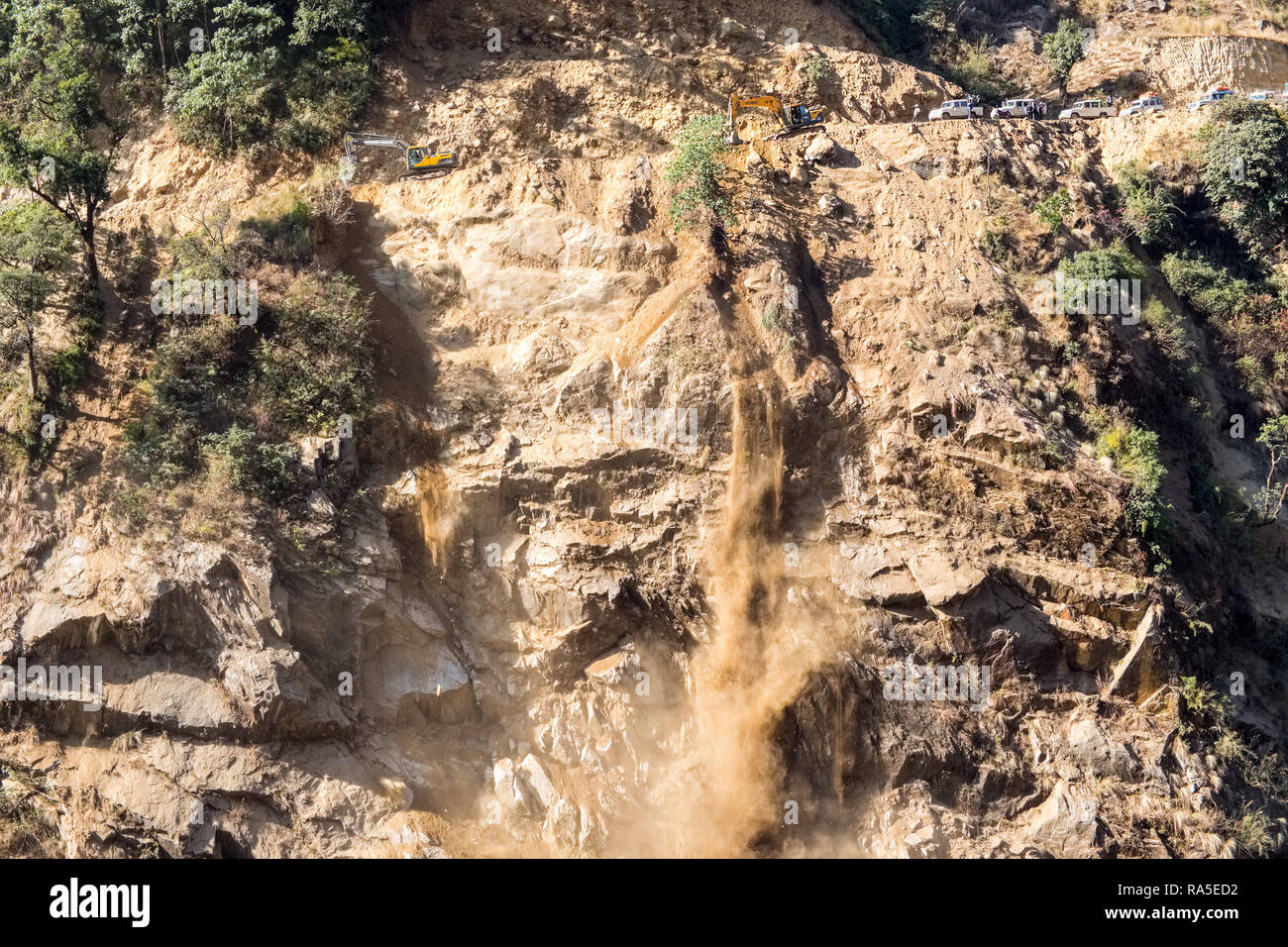Road construction work sending dirt and rubble down a hillside in the Nepal Himalayas Stock Photo