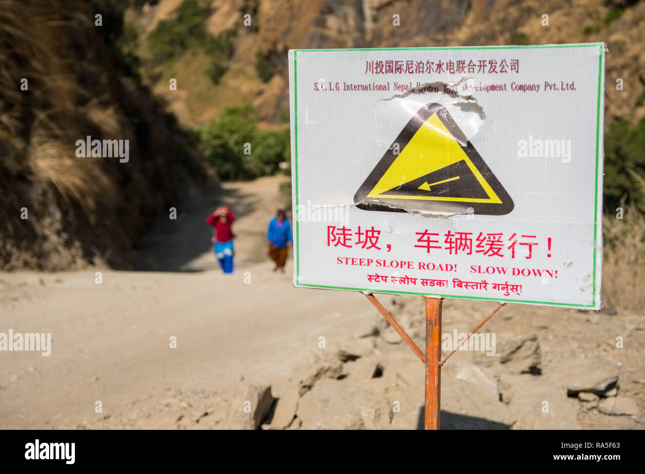 Road sign in Chinese on Chinese funded road building project, Nepal Himalayas Stock Photo