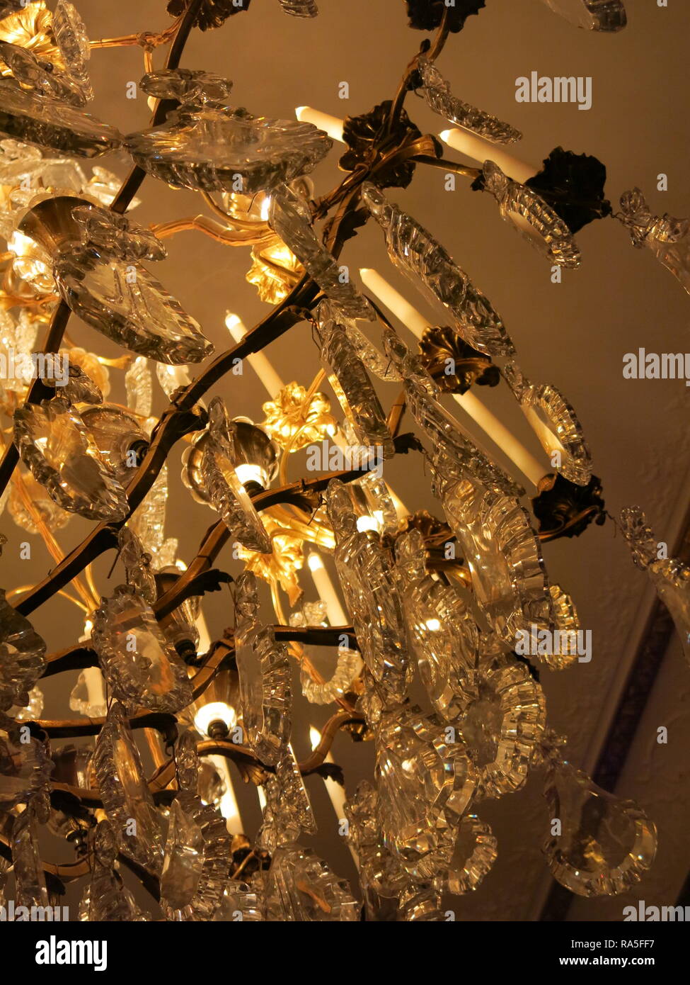 Closeup of an ornate, illuminated, crystal chandelier at Waddesdon
