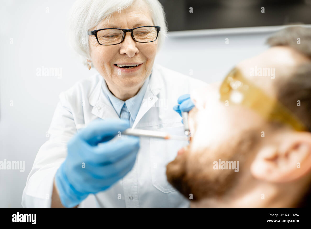 Elderly experienced dentist making dental examination to the male patient Stock Photo