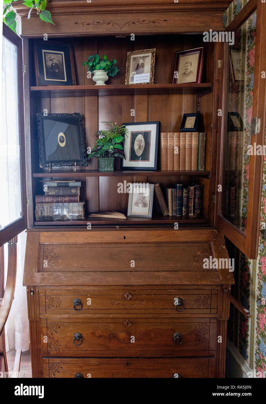 Antique wooden shelves and chest of drawers with antique photos and old ragged books. Interior of old Texan home, Chestnut Square, McKinney Texas. Stock Photo