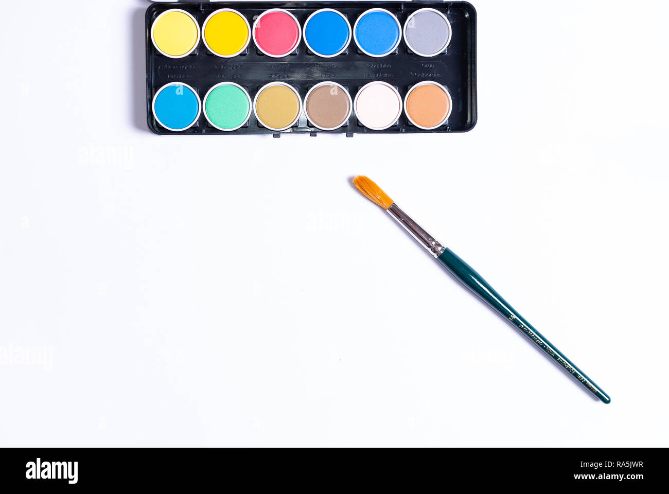 Flat lay of a colorful painting set and a paintbrush on white background with copy space Stock Photo