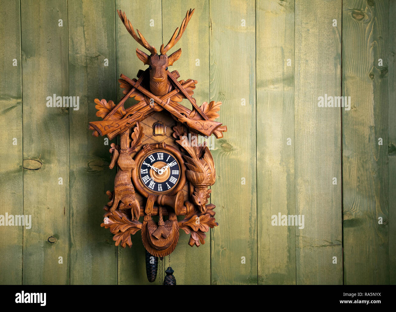 old black forest cuckoo clock in front of wooden wall Stock Photo