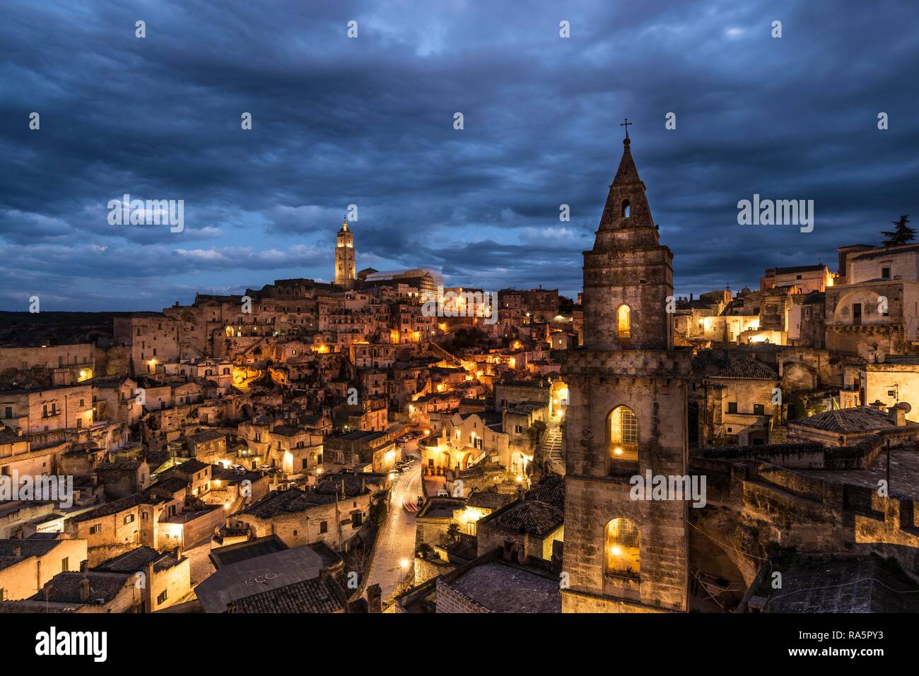 Church tower San Pietro Barisano in front of illuminated old town with cathedral, blue hour, Matera, Basilicata, Italy Stock Photo