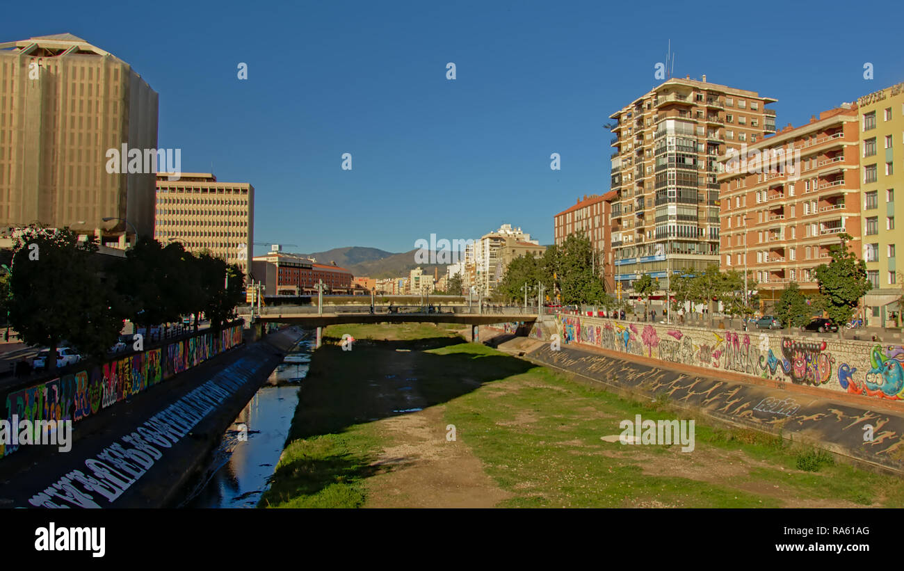 Guadalmedina, dried out river in Malaga with graffiti on the sides and apartment buildings. Only if it rains a lot in the mountains there is water in Stock Photo