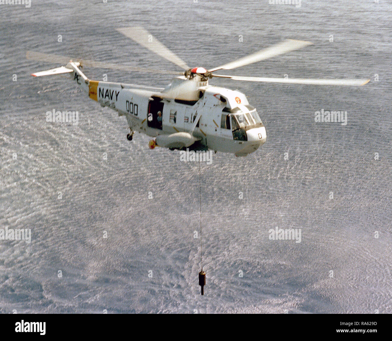 1979 - A right front view of an SH-3 Sea King helicopter from Helicopter Antisubmarine Squadron 15 (HS-15) as it lowers a sonar probe to the water's surface. Stock Photo