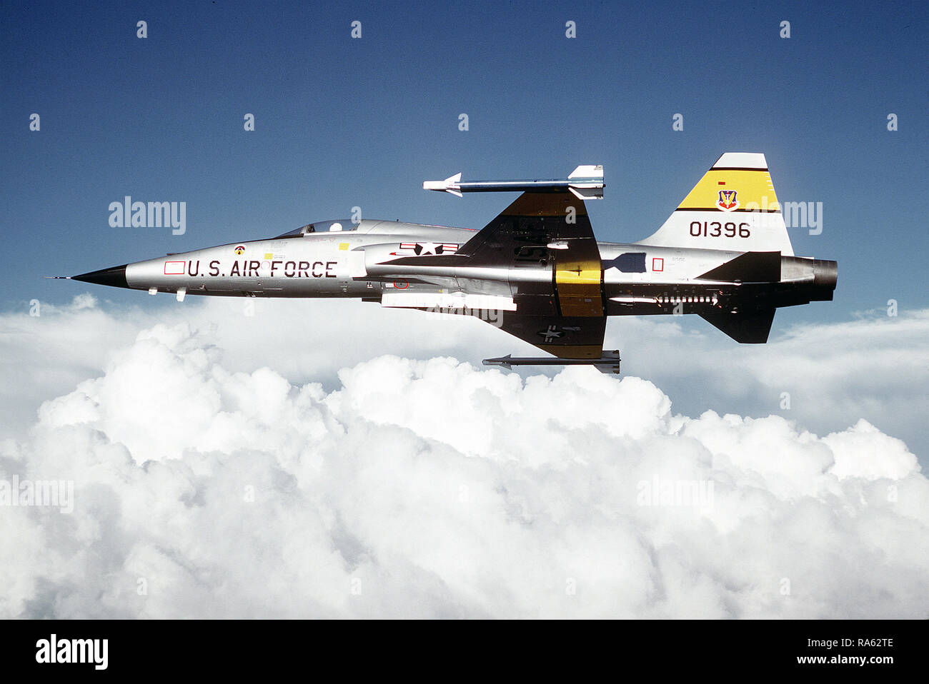 1979 - A left side view of an F-5 Tiger II aircraft carrying two AIM-9 Sidewinder missiles in flight. Stock Photo