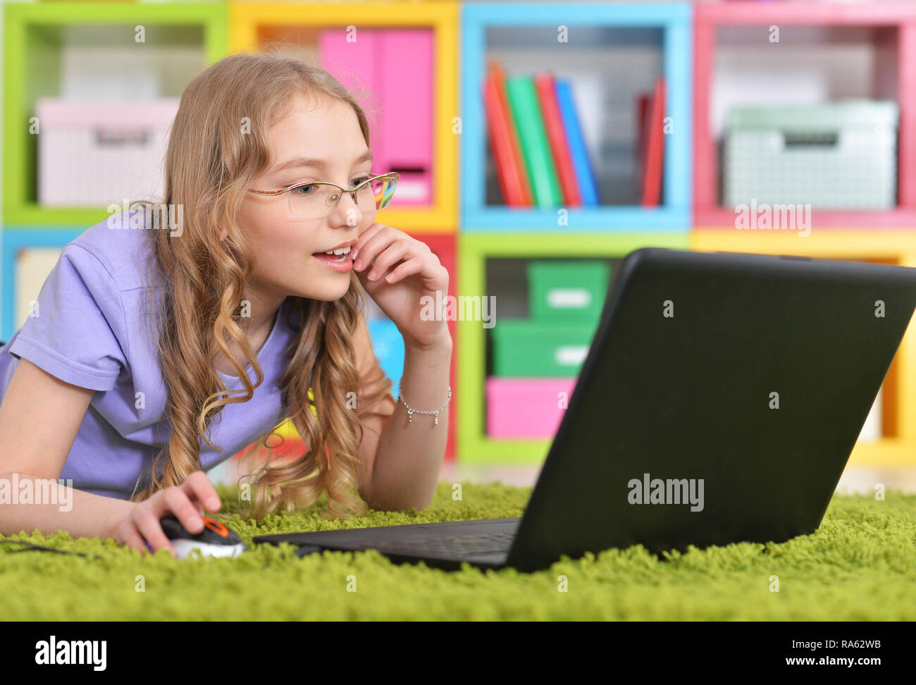 Emotional cute girl using laptop while lying on floor Stock Photo - Alamy