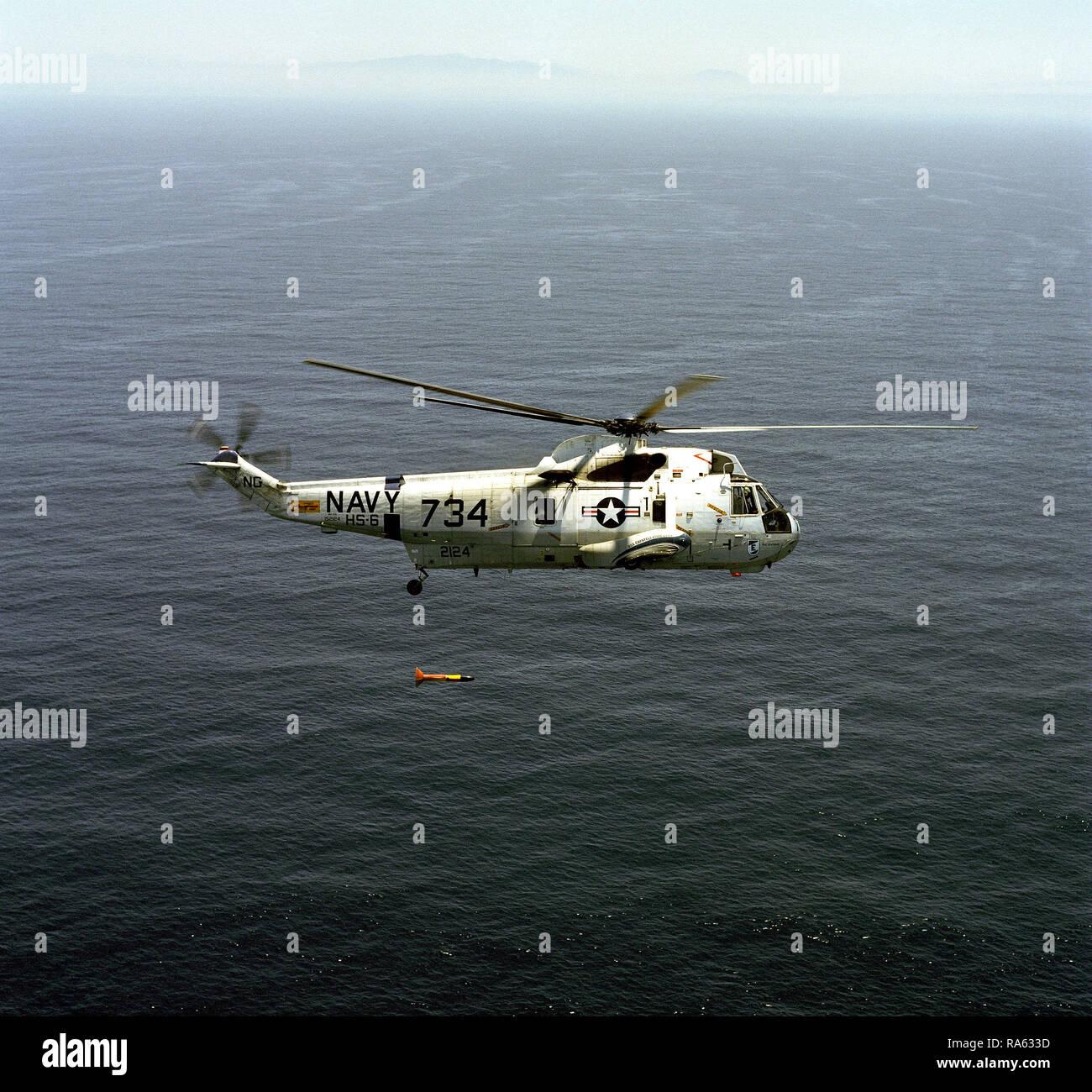 1976 - An air-to-air right side view of a Helicopter Anti-submarine Squadron 6 (HS-6) SH-3 Sea King helicopter with ASQ-81 magnetic anomaly detection (MAD) gear suspended below it during training operations off the coast of Southern California. Stock Photo