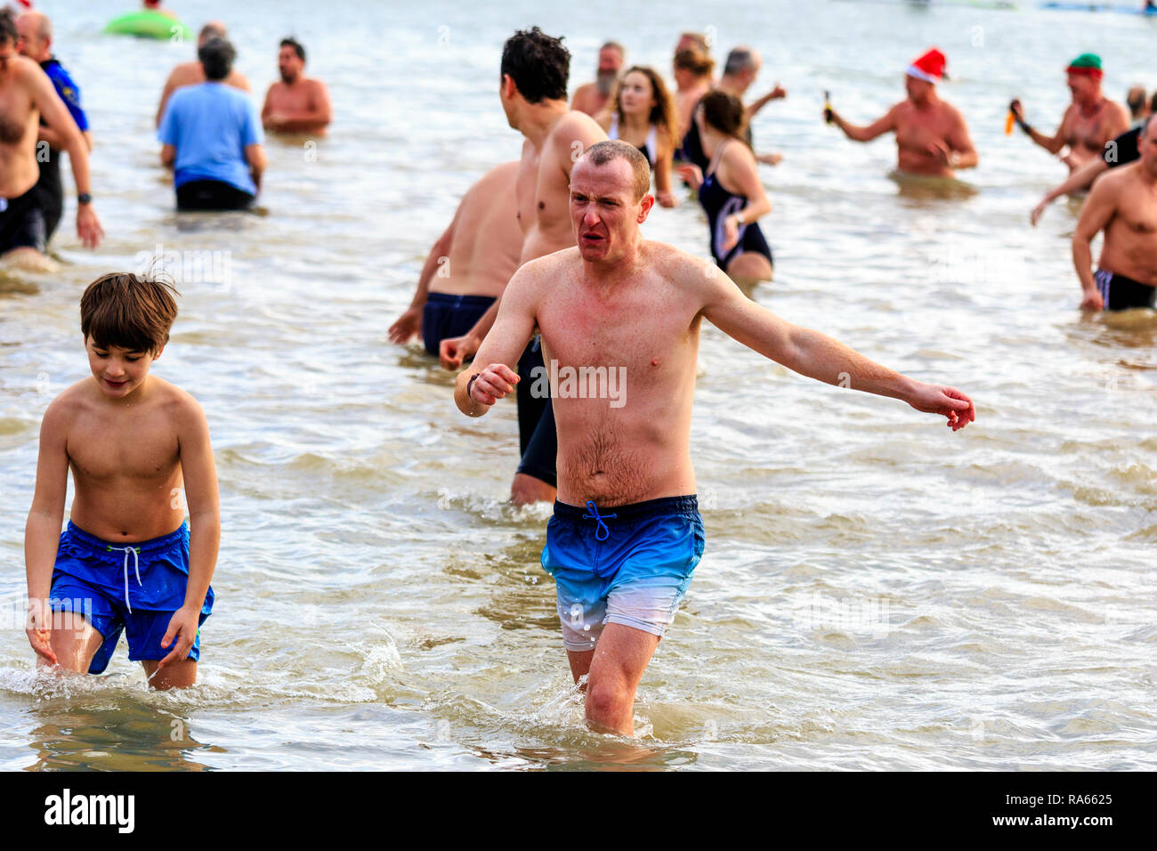 People in swim wear, wading into the sea for the traditional new Year Day dip or swim, a yearly charity event, at Viking Bay beach, Broadstairs. Stock Photo